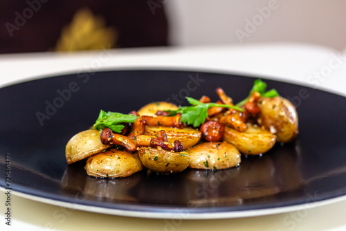 fried potatoes with chanterelle mushrooms and parsley on a black plate