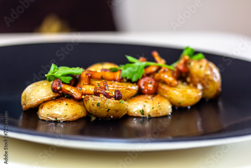 Fried potatoes with bacon and fresh parsley on a black plate