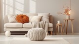 Knitted pouf near white fabric sofa with blanket and terra cotta pillows. Scandinavian, hygge style home interior design of modern living room