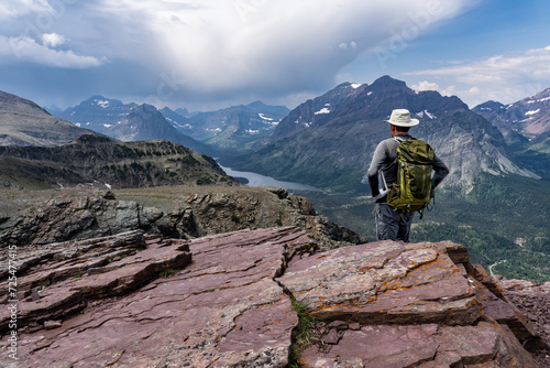 A hiker standing on a high point in the wilderness looking down at a valley with a lake, Two Medicine Lake from Scenic Point, Glacier National Park, Montana photo