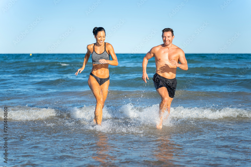 Middle aged couple exercising together on the beach this summer Middle aged couple exercising together on the beach this summer