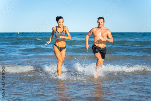 Middle aged couple exercising together on the beach this summer