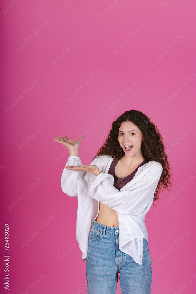 Enthusiastic woman with curly hair presenting with open hands, smiling in a white cardigan and jeans. Enthusiastic woman with curly hair presenting with open hands, smiling in a white cardigan and jeans.