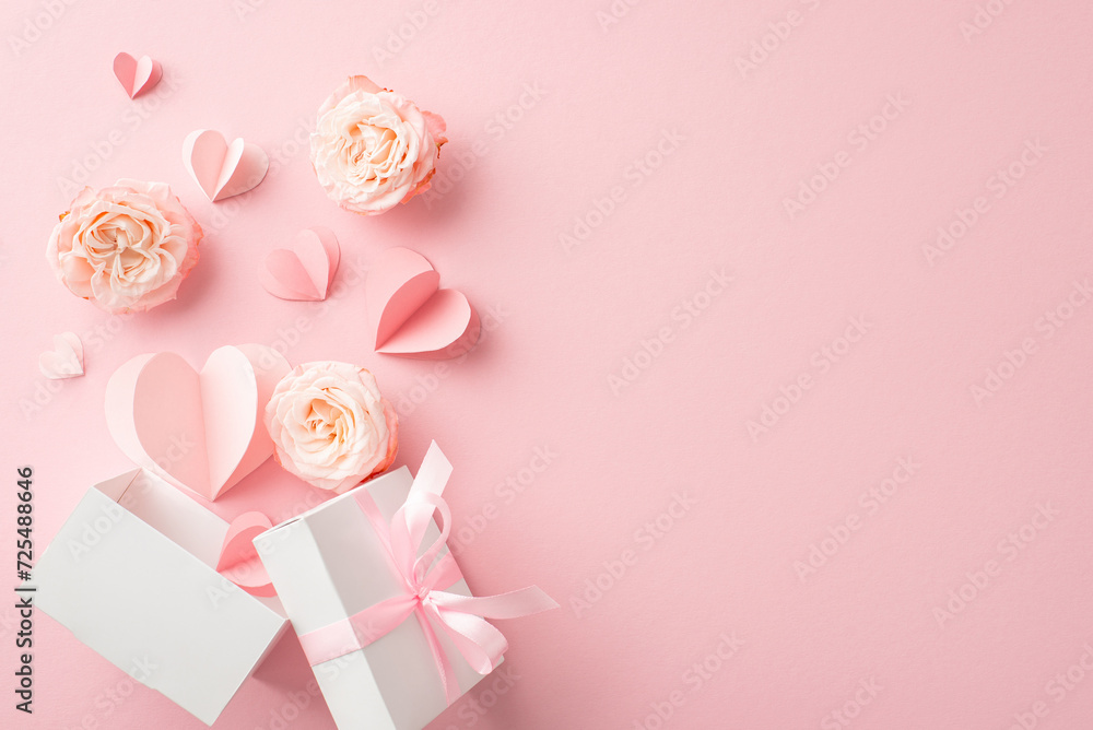 Shower your glamorous girlfriend with love! Top view shot of an open giftbox surrounded by blooming rosebuds, hearts on a pastel pink surface. Perfect for heartfelt messages or promotions
