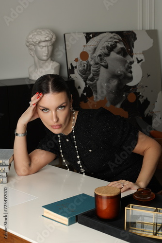 Serious business woman officially dressed in black twid dress. Beautiful  Office manager work at the table with books,  cup of tea. Lady portrait. Bookshelf photo