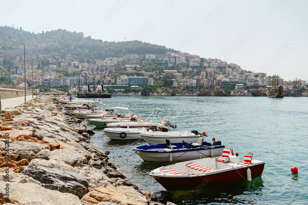 A peaceful Mediterranean seaside with anchored boats and ancient castle ruins overlooking the town from the hill