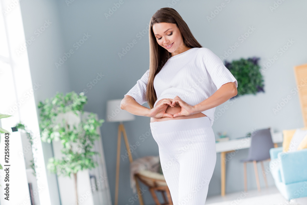 Photo of pretty sweet cute lovely mama pregnant lady showing heart touching big tummy waiting to meet with baby Photo of pretty sweet cute lovely mama pregnant lady showing heart touching big tummy waiting to meet with baby