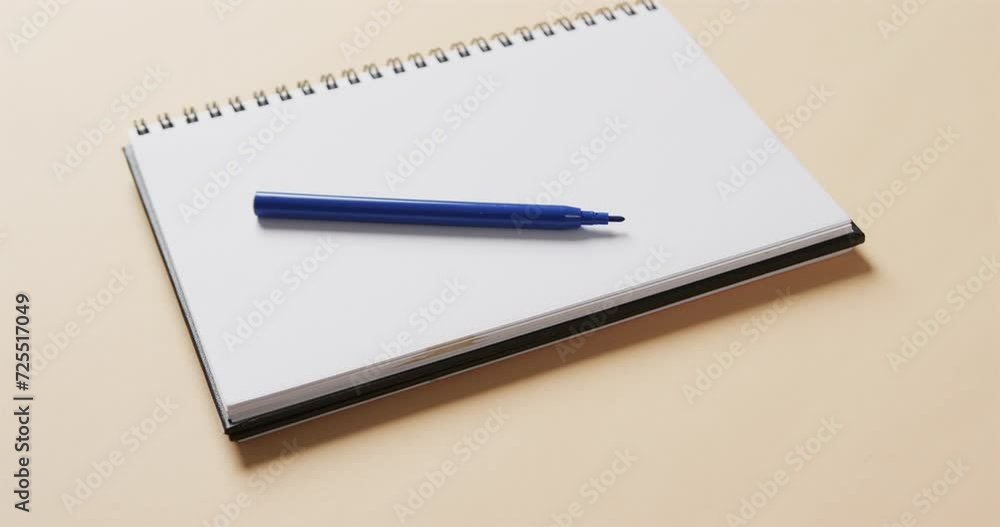 Close up of blue marker on notebook with beige background, in slow motion Close up of blue marker on notebook with beige background, in slow motion