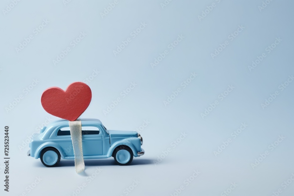 Blue retro toy car delivering heart for Valentine's day on blue background with copy space for advertiser Blue retro toy car delivering heart for Valentine's day on blue background with copy space for advertiser