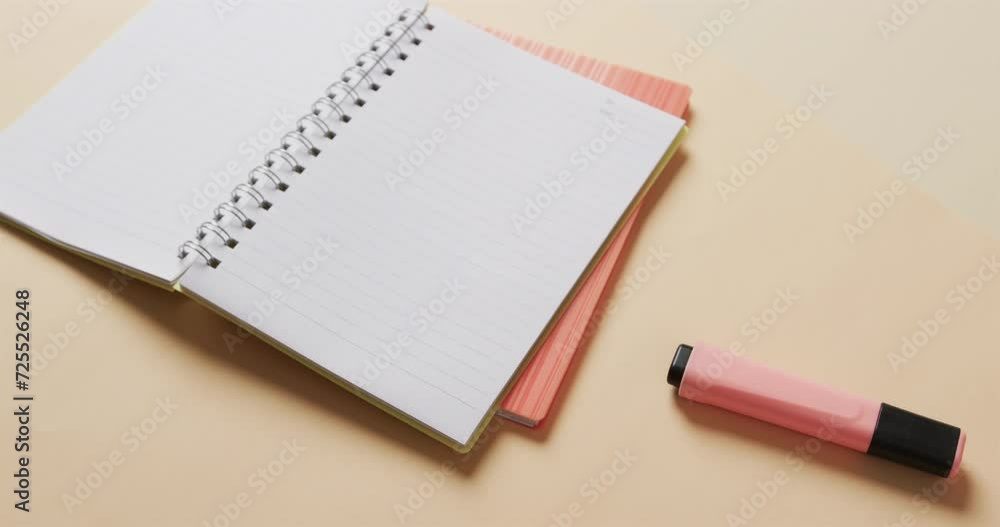 Close up of open notebook with pink marker on beige background, in slow motion Close up of open notebook with pink marker on beige background, in slow motion
