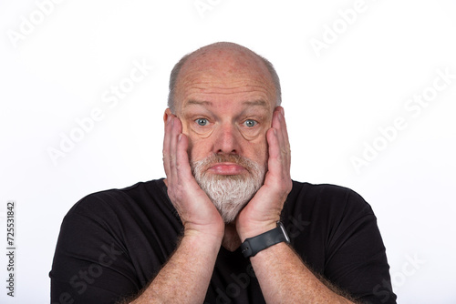 Stressed Middle-Aged Man in Black T-Shirt Expressing Shock and Despair on White Background