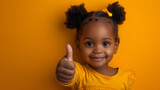 Happy little african american girl showing thumbs up gesture on yellow background