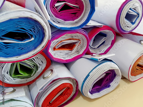 close-up of a bunch of rolled up banners in a room in the printing industry. piles of packed products on the workroom floor. colorful printed white tarpaulin