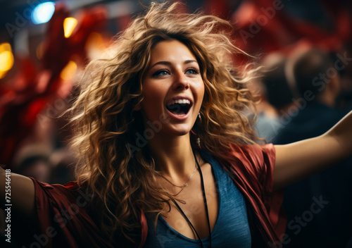 Female fan in stadium holding up arms in a sports bar. A woman joyfully celebrates as she raises her arms in the air, expressing elation and triumph.