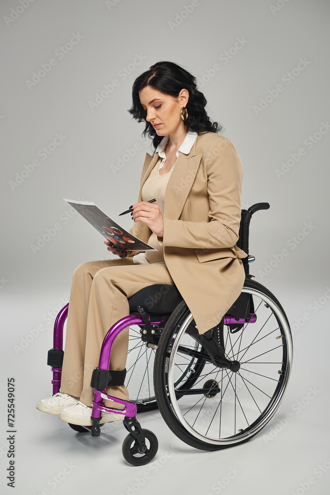 disabled confident woman in elegant attire sitting in wheelchair and working on her graphics disabled confident woman in elegant attire sitting in wheelchair and working on her graphics