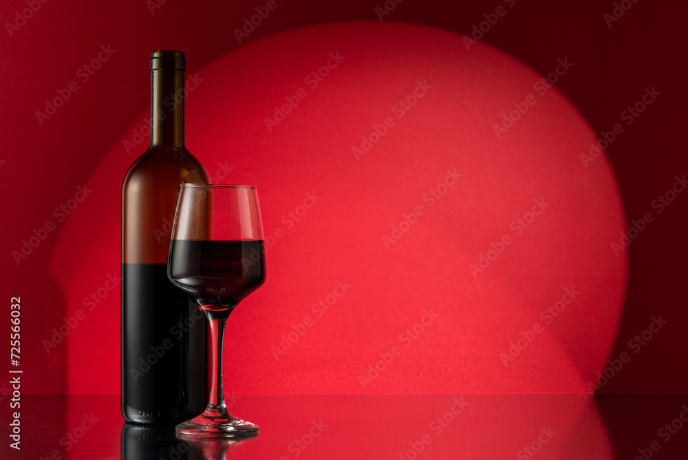 Glass and bottle of red wine on red background. Wine concept.
