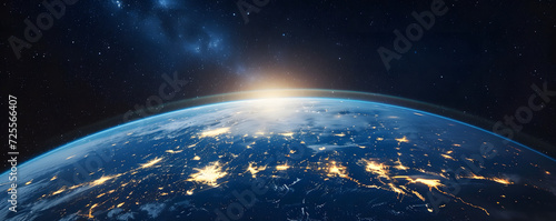 Earth shot from space, displaying shining lights, stars, and a dark blue galaxy in a panoramic view. The image captures the beauty of our planet and its atmospheric urbanscapes from a cosmic perspecti