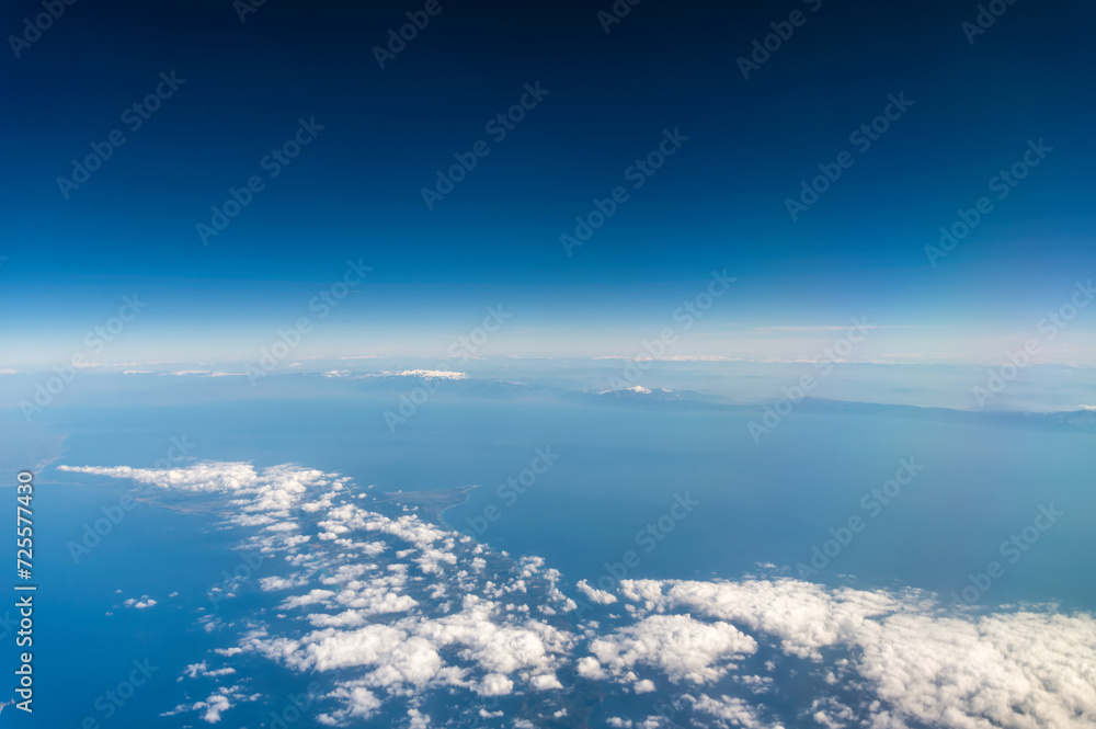 view from the airplane window to mountains clouds and blue sky