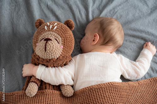 Little baby boy with toy in bed, handmade pajama bag, sleepwear organizer