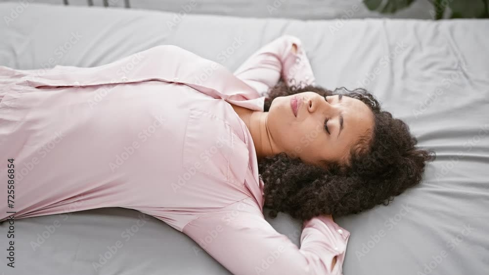 Easy morning, beautiful young hispanic woman relaxes, lying on bed in pjs, hands on head, expressive comfort in cozy bedroom Easy morning, beautiful young hispanic woman relaxes, lying on bed in pjs, hands on head, expressive comfort in cozy bedroom
