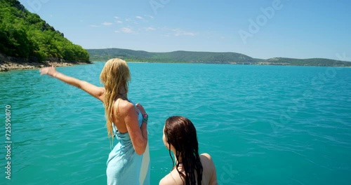 Women, friends and ocean or wave on beach or swimming vacation on tropical island for summer, adventure or travel. Female people, hand gesture and towel by water for holiday relax, paradise or hello photo