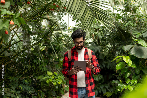 Hindu man with tablet in hands in botanical garden