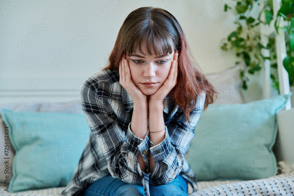 Upset sad young female sitting on couch at home Upset sad young female sitting on couch at home