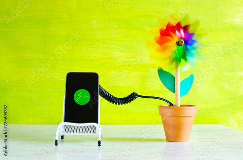 Charging mobile devices with green sustainable energy, smartphone and toy wind turbine, conceptual , free copy space