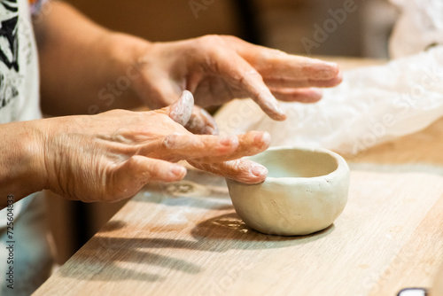 Woman's hands making a ceramic vessel from clay.