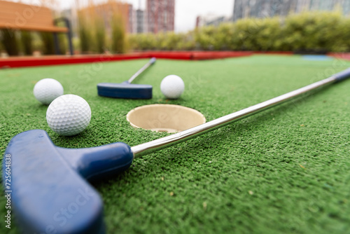 Assorted miniature golf putters and balls askew on synthetic grass.