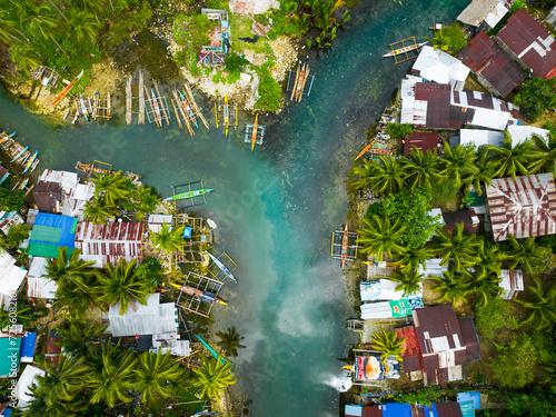 Flying over the turquoise cold water and houses of fishermen. Bogac Cold Spring. Surigao del Sur. Philippines. photo