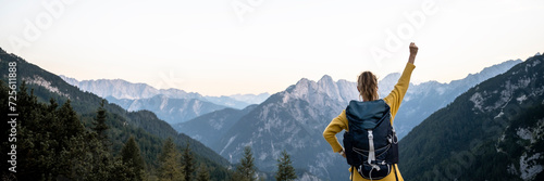Female hiker standing with her arm raised in victory looking at beautiful mountain view