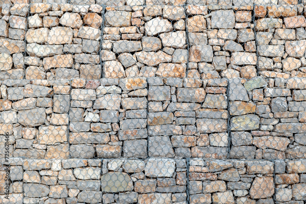 Empty grey stonewall behind wire metal mesh for protection background texture. Copy space