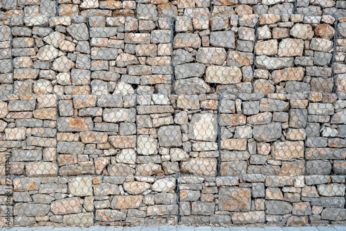 Empty grey stonewall behind wire metal mesh for protection background texture. Copy space
