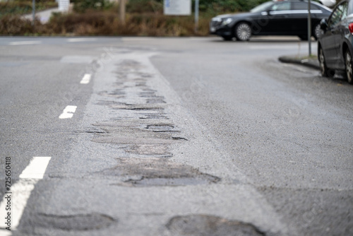 Asphaltstraße mit Schlagloch und Rissen