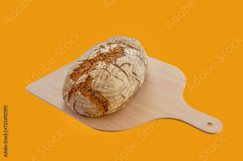Frisch gebackenes Brot auf einer Holzschaufel vor einem braunen Hintergrund