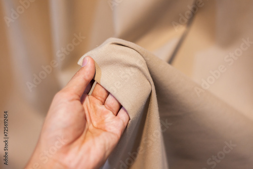 Hand Soft touch natural fabric. The hand is holding the white cloth for choosing a good fabric. © kheartmanee