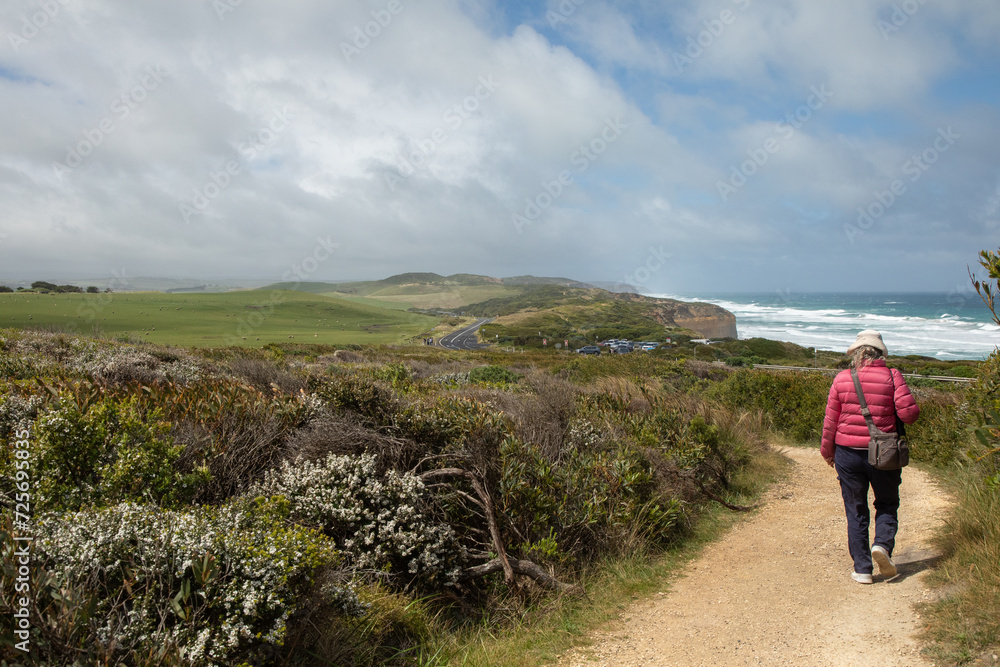 A tourist wanders on a path in Port Campbell National Park, Victoria, Australia, off the the Great Ocean Road overlooking the Bass Strait.