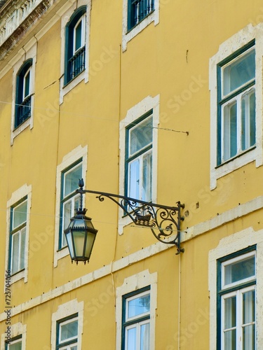 Vintage facade of yellow colour with decorated metallic street lamp on it in Lisbon, Portugal. Vertical photo
