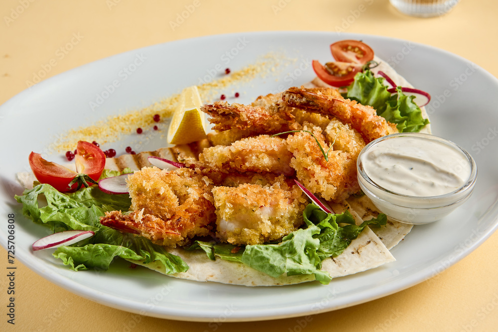 Tempura shrimp with tartar sauce on a bed of lettuce, presented on a white plate with lemon and tomato accents, against a soft yellow backdrop Tempura shrimp with tartar sauce on a bed of lettuce, presented on a white plate with lemon and tomato accents, against a soft yellow backdrop