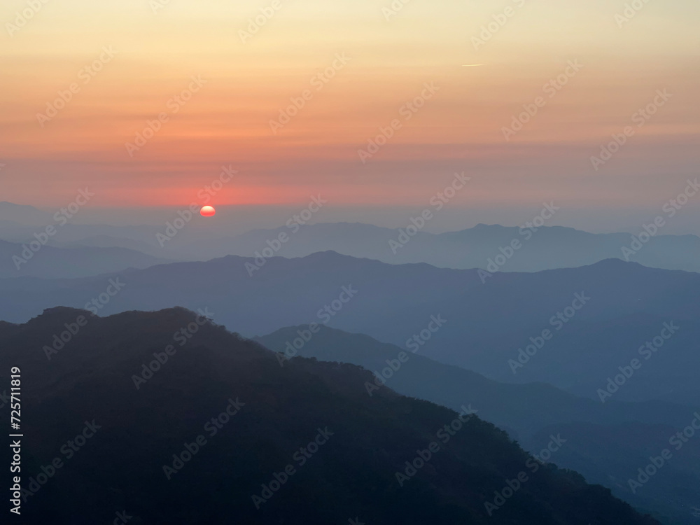Sunset over mountains silhouetted in the distance