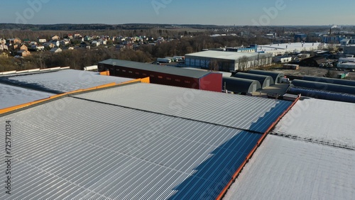 The metal roof of a huge warehouse, a storage facility. Roof made of spherical metal profile. Snow-covered roof in winter. Snow on the roof of the building.