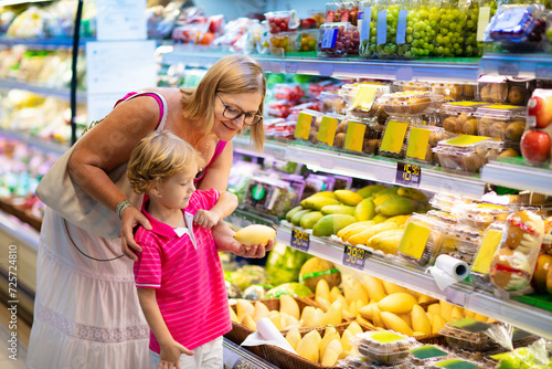 Mother and child buying fruit in supermarket.