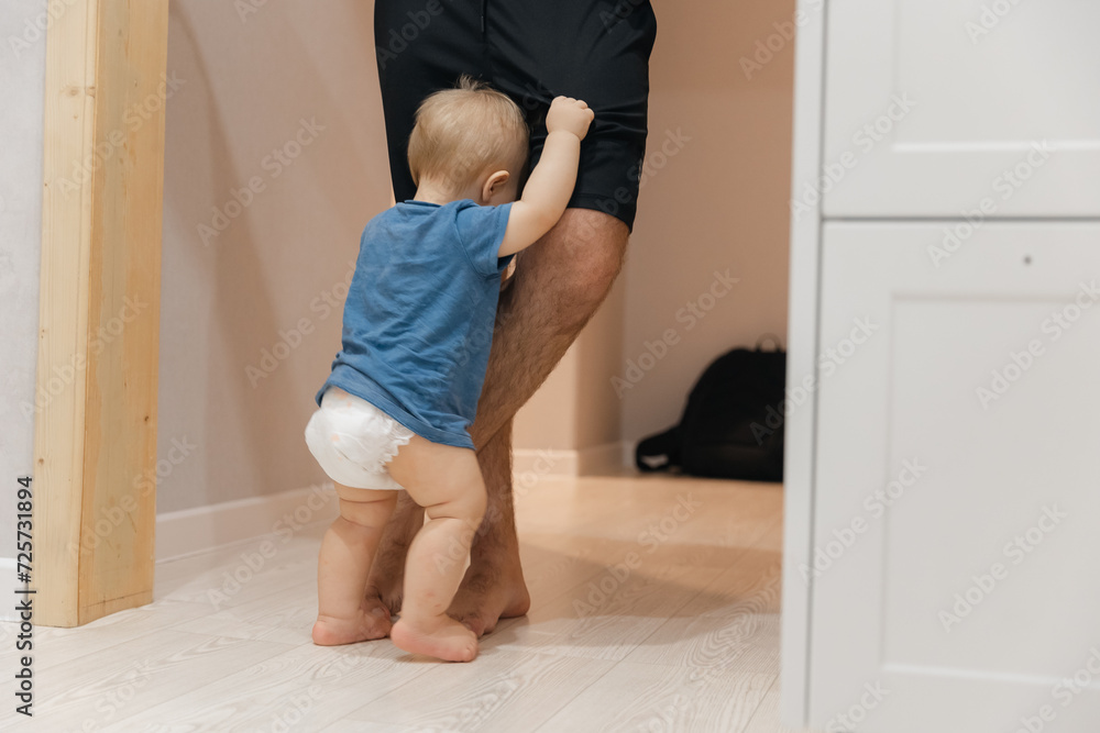 Little boy buried himself in his father legs for support and hiding his fears. Concept dad presence in child life, lifestyle moment in fatherhood Little boy buried himself in his father legs for support and hiding his fears. Concept dad presence in child life, lifestyle moment in fatherhood