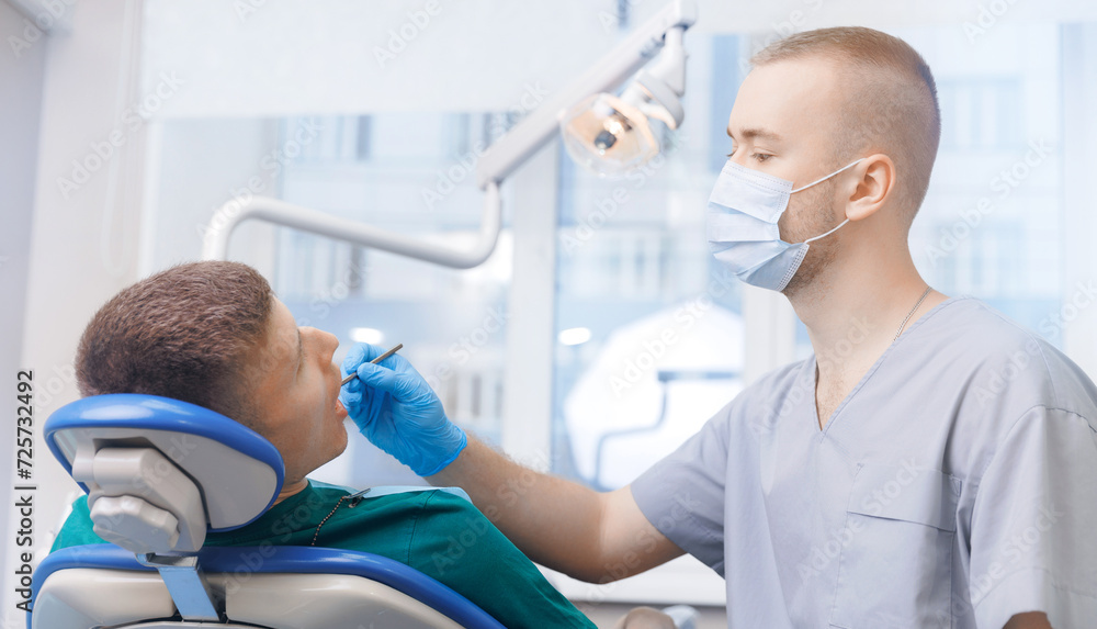 Dentistry clinic banner, young men getting dental checkup. Dentist using equipment probe and mirror for examination of teeth of man patient Dentistry clinic banner, young men getting dental checkup. Dentist using equipment probe and mirror for examination of teeth of man patient