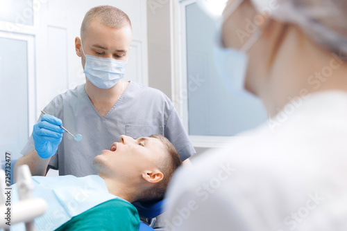 Dentistry clinic banner, young men getting dental checkup. Dentist using equipment probe and mirror for examination of teeth of man patient