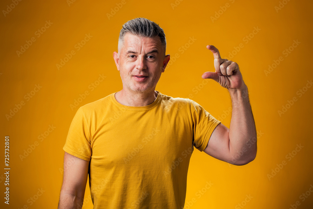 Man doing small size sign with fingers looking and the camera. Measure concept. Man doing small size sign with fingers looking and the camera. Measure concept.