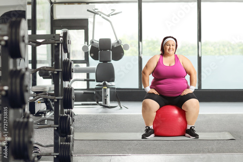 Corpulent woman sitting on a fitness ball at a gym