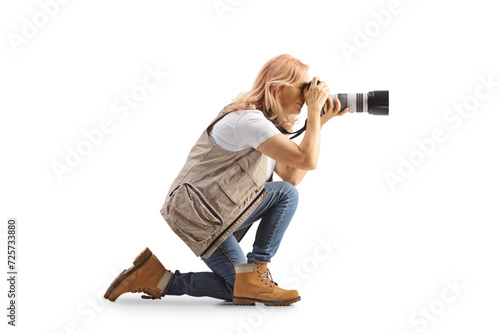 Full length profile shot of a female photographer kneeling and taking a photo photo