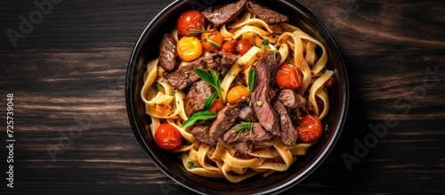 Top view Fettuccine pasta with beef in black bowl. Background Copy space